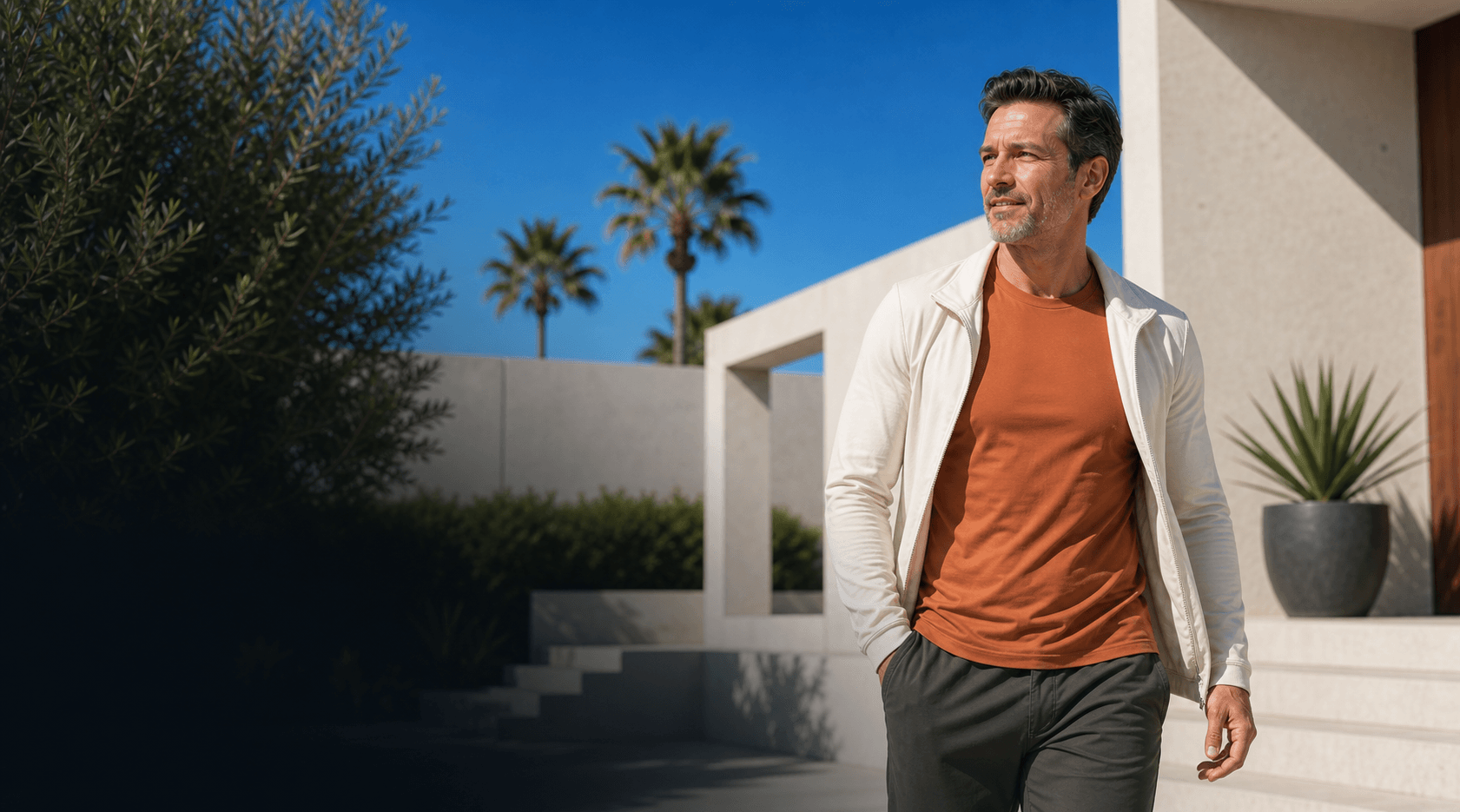 Adult in terracotta activewear walking through a sunlit modern courtyard for sleep and fatigue review.
